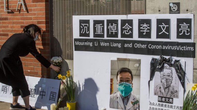 Los estudiantes chinos y sus partidarios sostienen un monumento en memoria del Dr. Li Wenliang, quien fue el denunciante del coronavirus que se originó en Wuhan, China y causó la muerte del doctor en esa ciudad, en las afueras del campus de la UCLA en Westwood, California, el 15 de febrero de 2020. (Mark Ralston/AFP vía Getty Images)