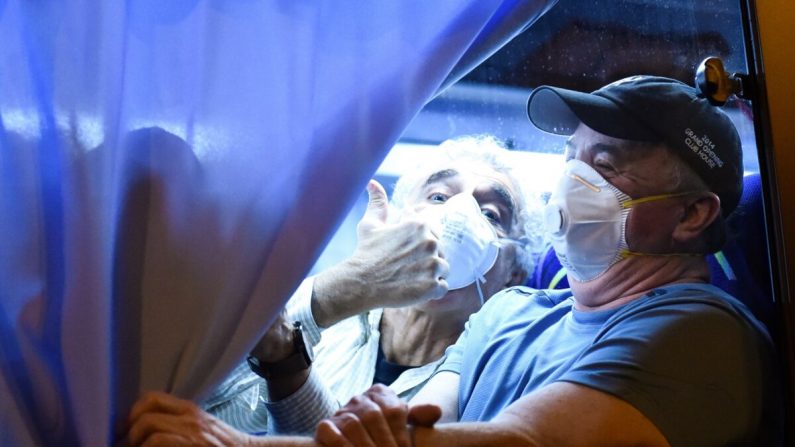 Un pasajero estadounidense saluda a los periodistas al llegar al aeropuerto de Haneda en Tokio el 17 de febrero de 2020. (Kazuhiro Nogi/AFP a través de Getty Images)