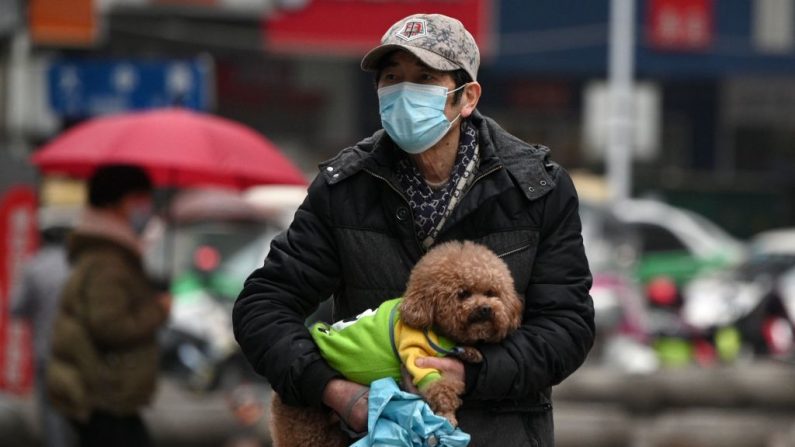 Un hombre con una máscara facial lleva a su perro a lo largo de una calle en Jiujiang en la provincia central de Jiangxi en China el 6 de marzo de 2020. (NOEL CELIS/AFP vía Getty Images)