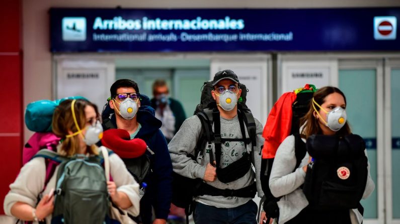 Pasajeros con máscaras faciales como medida preventiva contra la propagación del COVID-19 llegan al Aeropuerto Internacional de Ezeiza en Buenos Aires (Argentina), el 12 de marzo de 2020. (Foto de RONALDO SCHEMIDT/AFP vía Getty Images)
