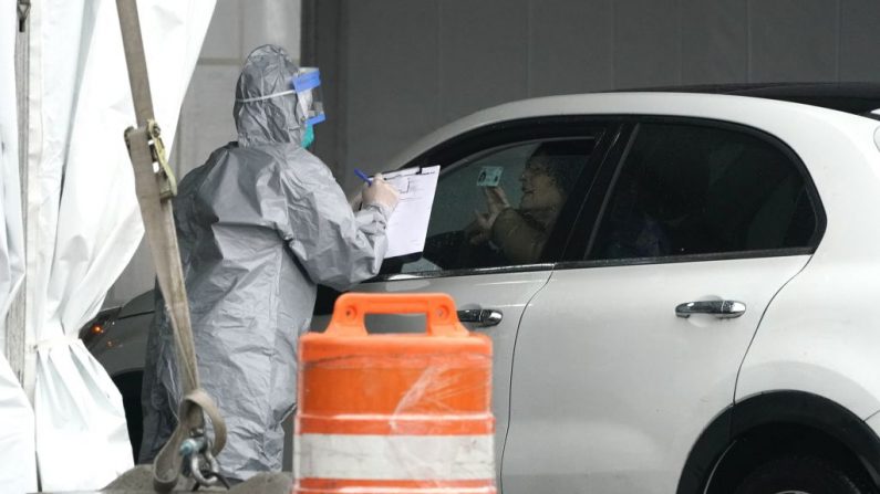 Trabajadores en trajes protectores revisan las identificaciones de los pacientes cuando llegan en coche para ser examinados por Coronavirus (COVID-19) en el Centro Móvil de Pruebas del Estado en Glen Island Park en New Rochelle, Nueva York, el 13 de marzo de 2020. (TIMOTHY A. CLARY/AFP/Getty Images)