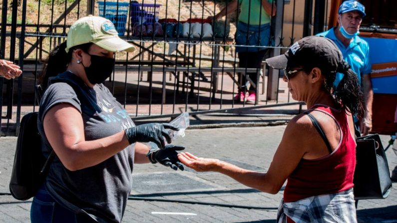 Una mujer recibe un desinfectante de manos en una unidad móvil de lavado de manos en San José, Costa Rica, el 28 de marzo de 2020 como medida preventiva contra la propagación del virus del PCCh. (EZEQUIEL BECERRA/AFP vía Getty Images)