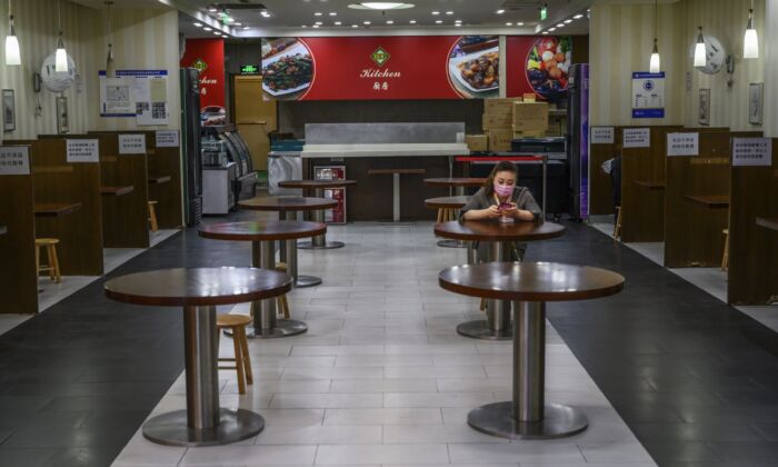 Mujer china espera a los clientes en un restaurante casi vacío en un centro comercial de Beijing, China, el 26 de marzo de 2020. (Kevin Frayer/Getty Images)