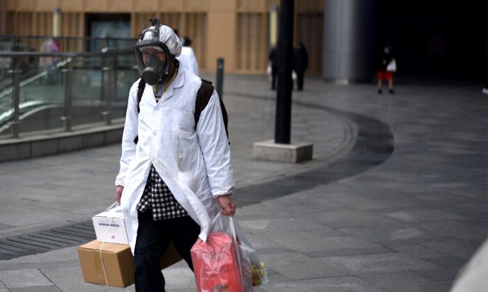 Un hombre con una máscara lleva artículos que compró en un supermercado de Wuhan, China, el 30 de marzo de 2020. (Noel Celis/AFP a través de Getty Images)