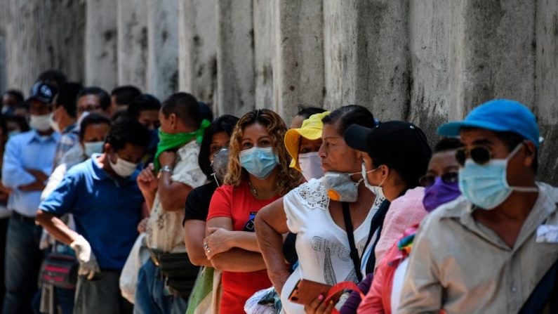 La gente usa máscaras contra la propagación del virus del PCCh mientras hace cola para entrar en un banco de San Salvador (El Salvador) el 30 de marzo de 2020. (YURI CORTEZ/AFP vía Getty Images)