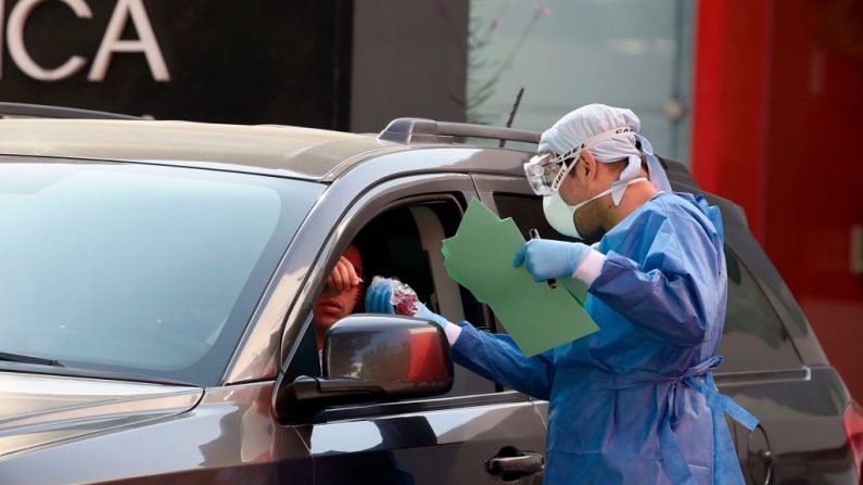Un médico entrega documentos a una persona en un coche como un cuestionario se hace antes de la prueba de COVID-19 en el Laboratorio Biomédico de la Ciudad de México (México) el 30 de marzo de 2020. (ALFREDO ESTRELLA/AFP vía Getty Images)