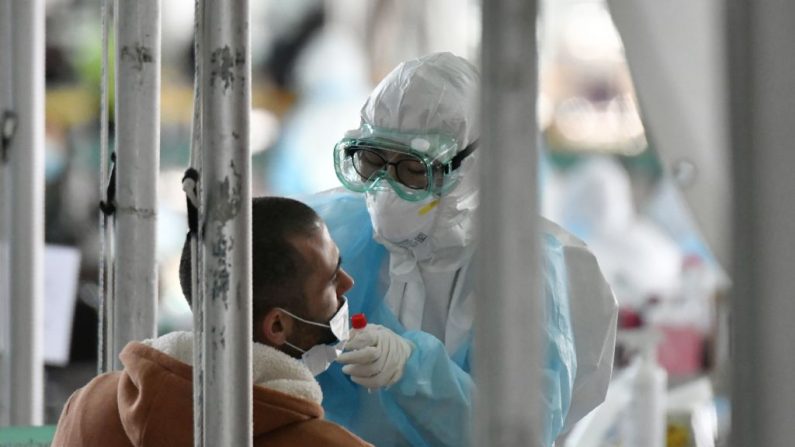Un personal médico con ropa de protección toma muestras de prueba para el coronavirus COVID-19 de un pasajero extranjero en una cabina de pruebas de virus en las afueras del aeropuerto internacional de Incheon, al oeste de Seúl, el 1 de abril de 2020.( JUNG YEON-JE/AFP vía Getty Images)