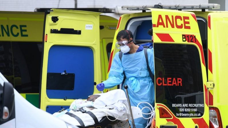 Un profesional médico en EPP, con guantes, protección ocular y una mascarilla facial como medida de precaución contra el virus del PCCh, lleva un tanque mientras un paciente es trasladado de una ambulancia al Hospital de Santo Tomás en el norte de Londres, el 1 de abril de 2020. (DANIEL LEAL-OLIVAS/AFP vía Getty Images)