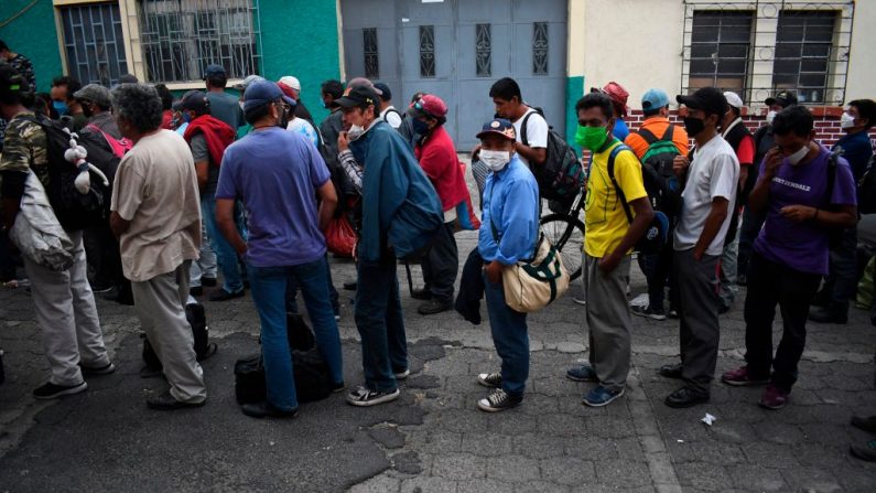 Hombres sin hogar usan máscaras faciales mientras hacen fila afuera de un refugio temporal durante el toque de queda parcial ordenado por el gobierno contra la propagación del virus del PCCh en la Ciudad de Guatemala, Guatemala, el 1 de abril de 2020. (JOHAN ORDONEZ/AFP vía Getty Images)