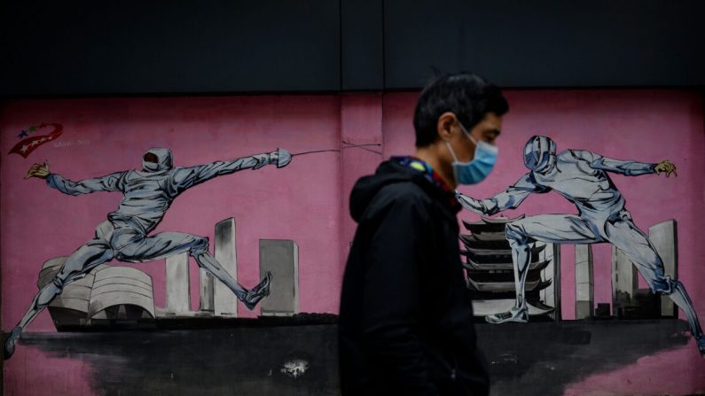 Un hombre con una máscara facial pasa junto a un mural a lo largo de una calle en Wuhan, provincia central de Hubei, China, el 2 de abril de 2020. (NOEL CELIS/AFP a través de Getty Images)