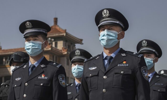 Agentes de policía chinos con mascarillas mantienen tres minutos de silencio durante el día nacional de luto por el virus del PCCh en la Estación de Ferrocarril de Beijing, China, el 4 de abril de 2020. (Kevin Frayer/Getty Images)