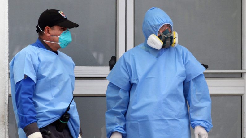 Un guardia de seguridad (i) y un médico esperan en la entrada del hospital Guasmo Sur de Guayaquil, Ecuador, el 4 de abril de 2020 durante la pandemia del virus del PCCh. (ENRIQUE ORTIZ/AFP vía Getty Images)