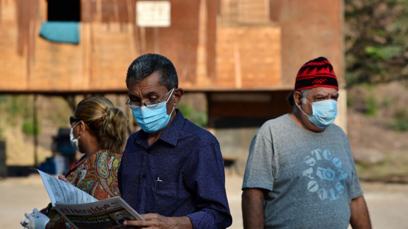 Un hombre lleva una máscara facial contra la propagación del virus del PCCh mientras lee el periódico en una calle de Tegucigalpa (Honduras), el 6 de abril de 2020. (ORLANDO SIERRA/AFP vía Getty Images)