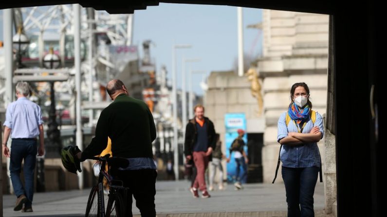 Una mujer que lleva una máscara facial como medida de precaución contra el COVID-19, pasa junto a un ciclista en la orilla sur, junto al río Támesis en el centro de Londres, Inglaterra, el 7 de abril de 2020. (ISABEL INFANTES/AFP vía Getty Images)