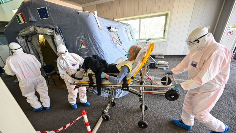 Trabajadores médicos con trajes protectores llevan a un paciente en una camilla a una tienda de primeros auxilios donde los pacientes que sufren de la enfermedad coronavirus (COVID-19) están siendo atendidos, en el hospital Policlínico di Tor Vergata en Roma el 7 de abril de 2020. (ANDREAS SOLARO/AFP vía Getty Images)