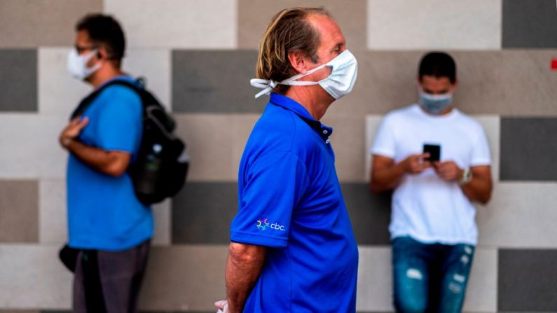 Las personas usan máscaras faciales para protegerse contra el virus del PCCh mientras mantienen su distancia en una cola en un supermercado durante un confinamiento obligatorio, en San Juan, Puerto Rico, el 7 de abril de 2020. (RICARDO ARDUENGO/AFP vía Getty Images)