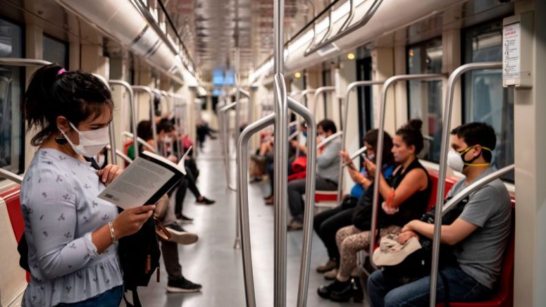 Una viajera usa una máscara facial como medida de precaución contra la propagación del virus del PCCh, mientras lee un libro en el metro de Santiago, Chile, el 8 de abril de 2020. (MARTIN BERNETTI/AFP vía Getty Images)