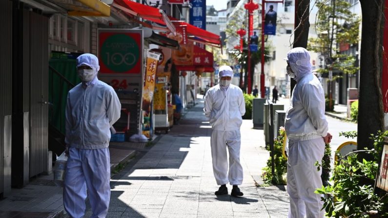 Los empleados de un restaurante con máscaras se paran fuera de su restaurante antes de que abra en el área del Barrio Chino en Yokohama, Japón, el 9 de abril de 2020. (PHILIP FONG/AFP vía Getty Images)