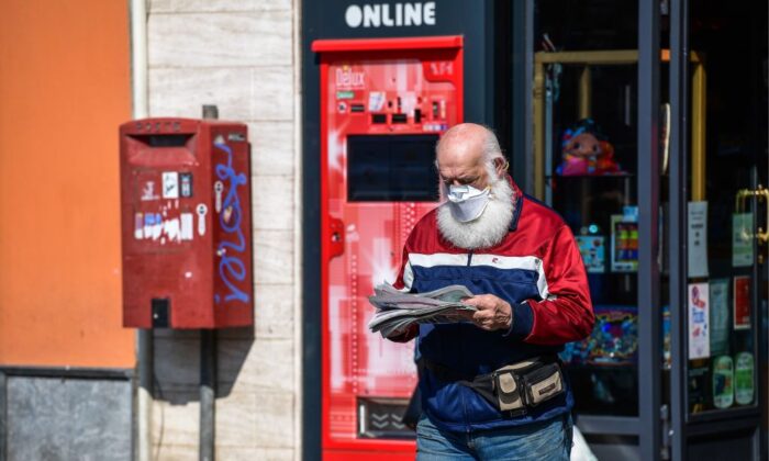 Un residente con una mascarilla sale de una tienda después de comprar un periódico en Treviolo, Italia, el 9 de abril de 2020. (Miguel Medina/AFP a través de Getty Images)