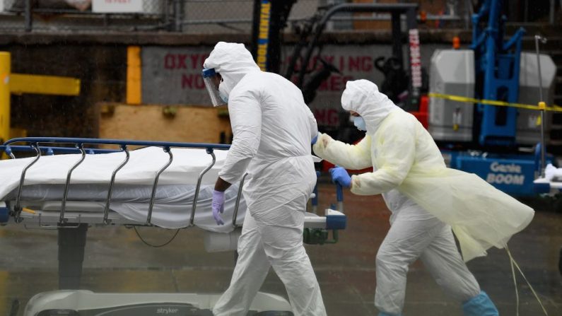 El personal médico traslada a un paciente fallecido a un camión frigorífico que sirve como morgue improvisada en el Centro Hospitalario de Brooklyn, en la ciudad de Nueva York, el 9 de abril de 2020. (Angela Weiss/AFP/Getty Images)
