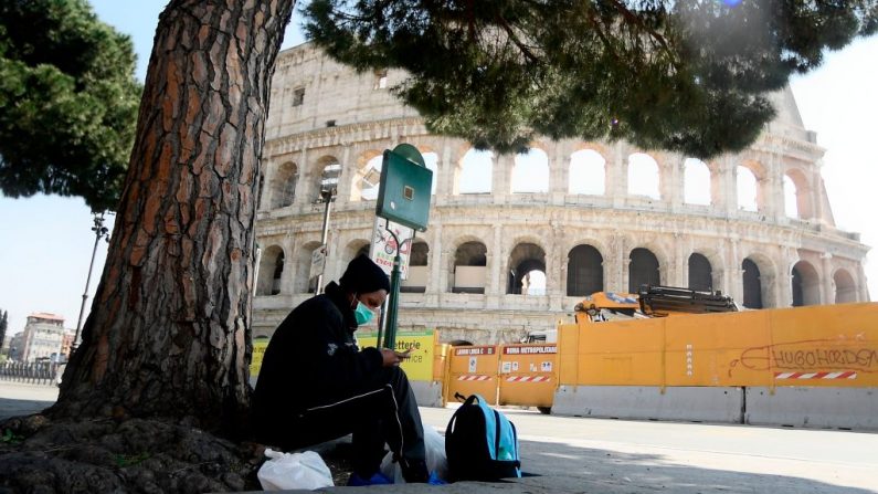 Un hombre revisa su smartphone junto al monumento del Coliseo en Roma, Italia, el 10 de abril de 2020 durante el cierre del país para frenar la propagación de la infección COVID-19, causada por el virus del PCCh. (FILIPPO MONTEFORTE/AFP vía Getty Images)