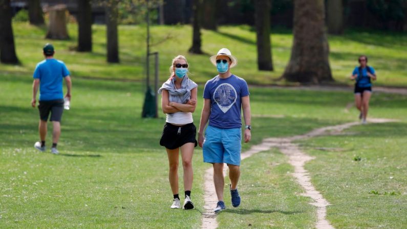 La gente usa máscaras para la cara mientras hacen su ejercicio diario en el Victoria Park en el este de Londres, Inglaterra, el 11 de abril de 2020. (TOLGA AKMEN/AFP vía Getty Images)