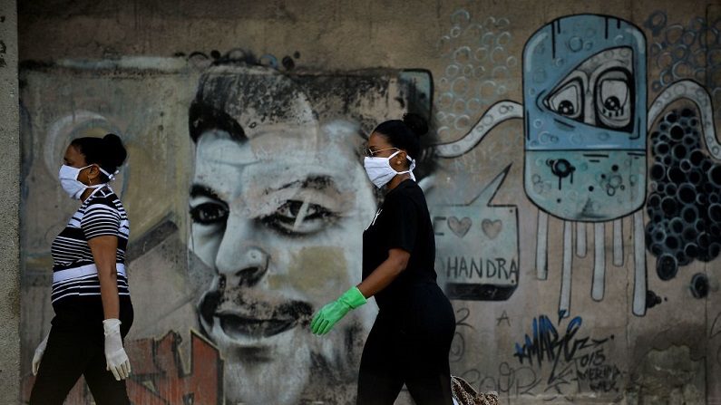 Las mujeres con mascarillas y guantes caminan por una calle de La Habana, Cuba, el 11 de abril de 2020. (YAMIL LAGE/AFP vía Getty Images)