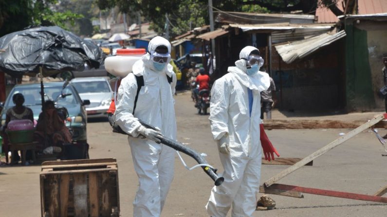 Trabajadores vestidos con ropa de cuerpo entero desinfectan tiendas y calles en Conakry (Guinea) el 12 de abril de 2020 durante una campaña de limpieza y desinfección como medida preventiva contra la propagación del COVID-19. (CELLOU BINANI/AFP vía Getty Images)