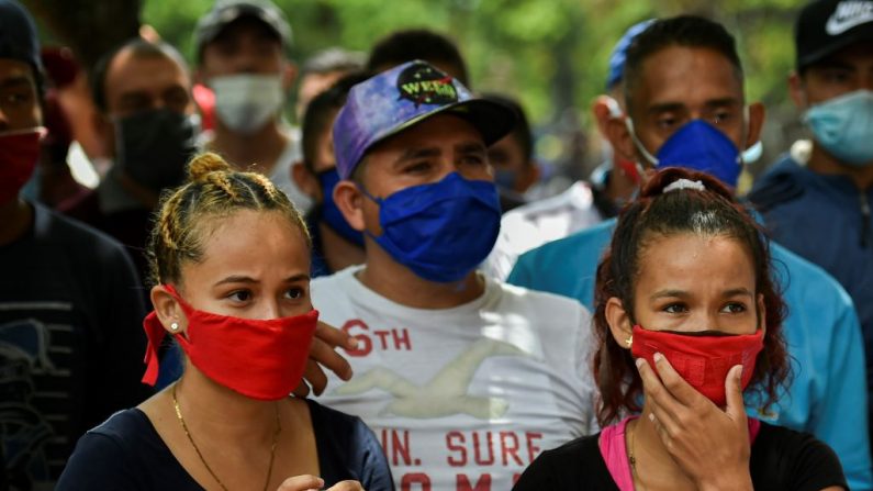 Migrantes venezolanos usan máscaras faciales mientras esperan ser revisados por trabajadores de la salud para descartar la COVID-19 como parte de su proceso de repatriación en Cali, Colombia, el 13 de abril de 2020. (LUIS ROBAYO/AFP vía Getty Images)