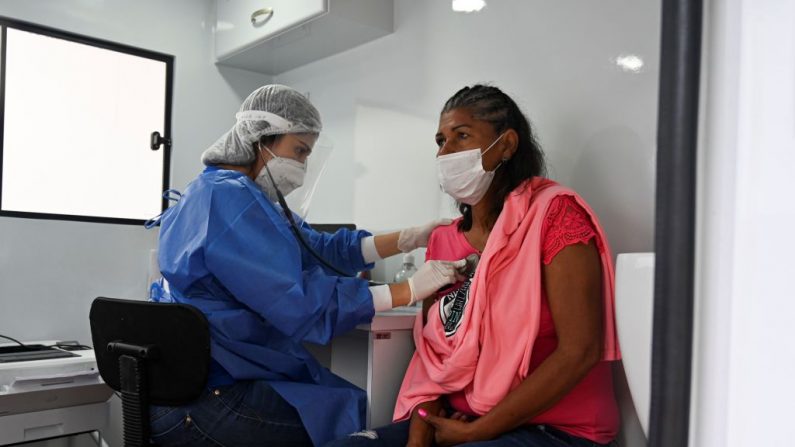 Un trabajador de la salud revisa a una migrante venezolana para descartar el virus del PCCh durante su proceso de repatriación en Cali, Colombia, el 13 de abril de 2020. (LUIS ROBAYO/AFP vía Getty Images)