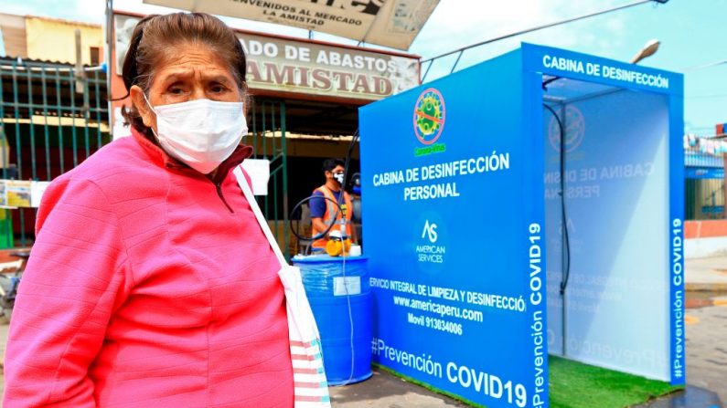 Una anciana con una máscara facial se prepara para entrar en una cabina de desinfección contra la propagación del virus del PCCh situada a la entrada del mercado de La Amistad en Moche, al norte del Perú, el 14 de abril de 2020. (CELSO ROLDAN/AFP vía Getty Images)