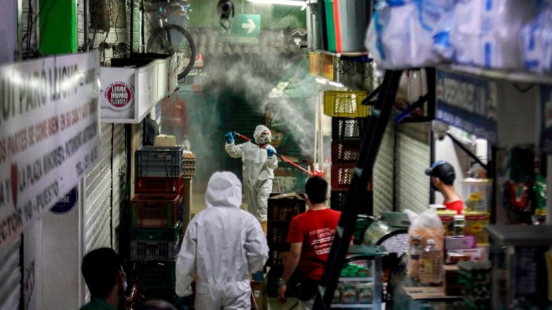Trabajadores con trajes especiales desinfectan los puestos del mercado minorista, después de que el alcalde Daniel Quintero anunciara un brote de COVID-19 en este mercado, en Medellín (Colombia) el 14 de abril de 2020. (JOAQUIN SARMIENTO/AFP vía Getty Images)