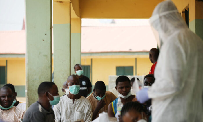 La gente espera mientras los trabajadores de la salud se preparan para tomar muestras durante una campaña comunitaria de test de virus del PCCh en Abuja (Nigeria) el 15 de abril de 2020. (Kola Sulaimon/AFP vía Getty Images)