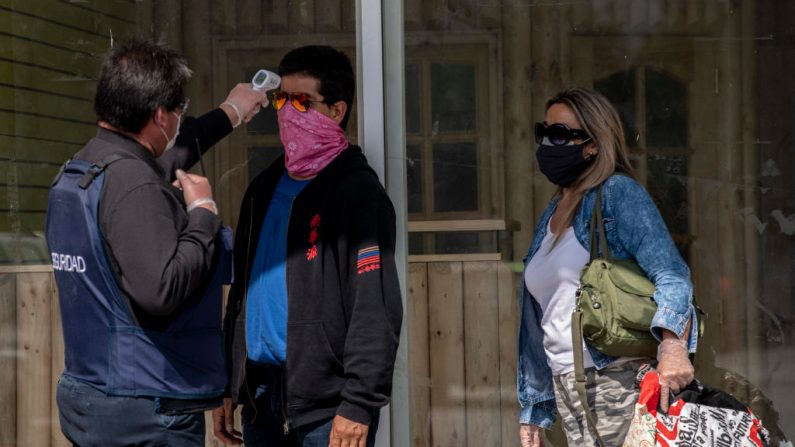 Un guardia de seguridad toma la temperatura de un hombre en la comuna de Del Bosque, en Santiago, Chile, el 15 de abril de 2020. (MARTIN BERNETTI/AFP vía Getty Images)