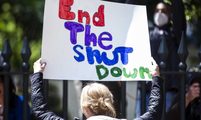 Un manifestante sostiene un cartel frente al Capitolio del Estado de Virginia en Richmond, Virginia, Estados Unidos, el 16 de abril de 2020. (Zach Gibson/Getty Images)