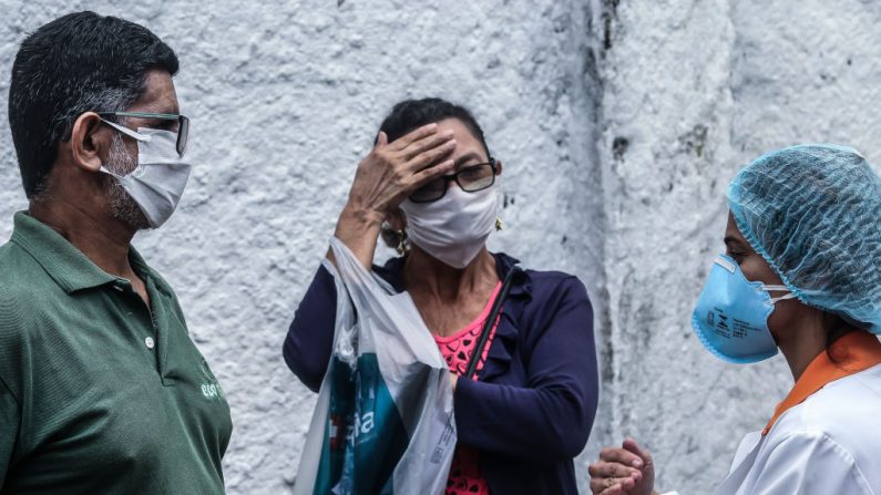 Una trabajadora de la salud con equipo de protección médica (d) habla con un paciente después de recibir resultado positivo en la prueba de COVID-19 en el Centro de Salud de Teixeira de Freitas el 17 de abril de 2020 en Niterói, Brasil. (Luis Alvarenga/Getty Images)