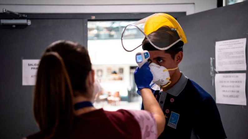 Una trabajadora de la salud revisa la temperatura corporal de un empleado en el Aeropuerto Internacional de Santiago, en Santiago (Chile), el 20 de abril de 2020 durante la nueva pandemia del virus del PCCh. (MARTIN BERNETTI/AFP vía Getty Images)