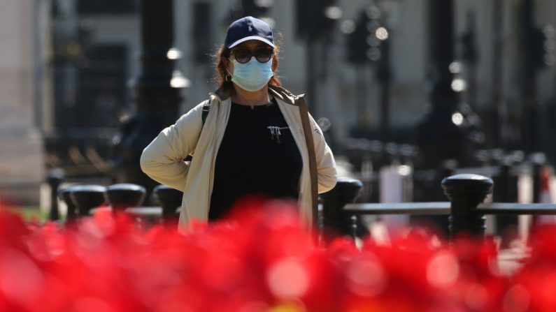 Una mujer que usa equipo de protección personal como medida de precaución contra COVID-19, camina entre las flores de primavera en el centro de Londres mientras Gran Bretaña permanece encerrada durante la crisis del coronavirus el 22 de abril de 2020. (ISABEL INFANTES/AFP vía Getty Images)