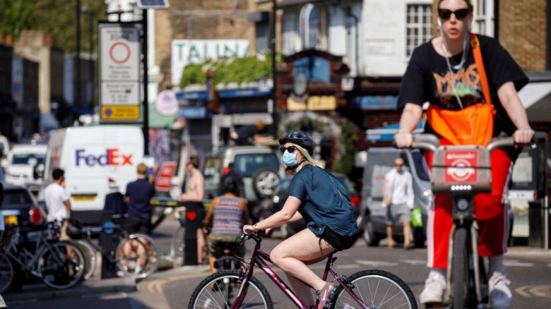 Una mujer con máscara facial pasa en bicicleta por el Broadway Market en el este de Londres, Inglaterra, el 24 de abril de 2020, durante el cierre nacional debido a la nueva pandemia del virus del PCCh. (TOLGA AKMEN/AFP vía Getty Images)