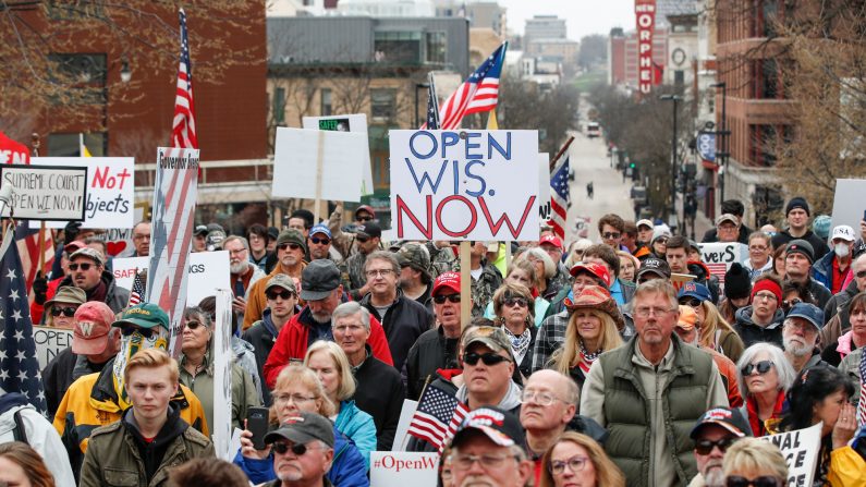 Personas sostienen carteles durante una protesta contra el cierre del coronavirus frente al Capitolio del Estado en Madison, Wisconsin, el 24 de abril de 2020. (KAMIL KRZACZYNSKI/AFP a través de Getty Images)
