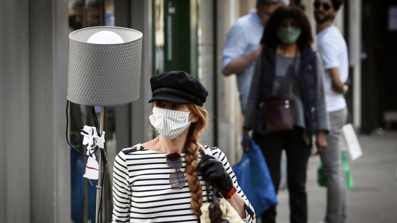 Una mujer con una máscara facial camina con una lámpara en una calle de París (Francia) el 25 de abril de 2020, el 40º día de un estricto bloqueo destinado a frenar la propagación de la pandemia COVID-19, causada por el virus del PCCh. (ALAIN JOCARD/AFP vía Getty Images)