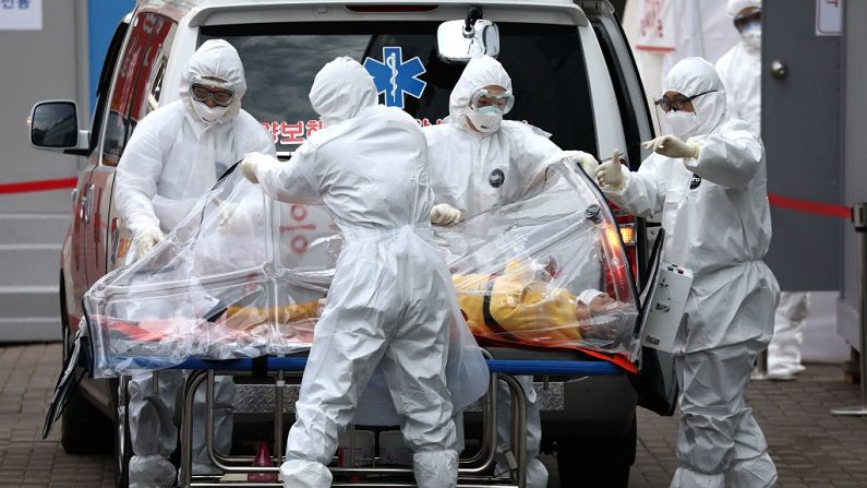 El personal médico, con equipos de protección, trasladan a un paciente infectado con el virus del PCCh desde una ambulancia a un hospital en Seúl, Corea del Sur, el 9 de marzo de 2020. (Chung Sung-Jun/Getty Images)