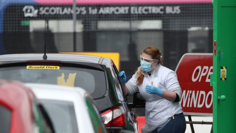 Una trabajadora médica examina a un trabajador clave para el virus del PCCh en un centro de pruebas en el aeropuerto de Glasgow el 29 de abril de 2020, mientras el Reino Unido continúa encerrado para ayudar a frenar la propagación de COVID-19. (ANDREW MILLIGAN/POOL/AFP vía Getty Images)