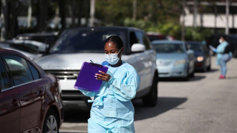 El personal de atención médica del centro FoundCare usa equipo de protección cuando ayuda a las personas que llamaron para concertar una cita para hacerse la prueba del virus del PCCh en el estacionamiento del centro el 16 de marzo de 2020 en West Palm Beach, Florida, EE.UU. (Joe Raedle/Getty Images)
