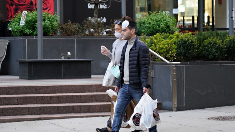Personas usando máscaras protectoras y fumando mientras el coronavirus continúa extendiéndose por los Estados Unidos el 26 de marzo de 2020 en la ciudad de Nueva York. (Cindy Ord/Getty Images)