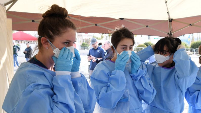 Estudiantes de medicina de la Universidad de Touro Nevada, Allison Boynton, Allison Moran y Claire Chen se ponen el equipo de protección personal para realizar exámenes médicos en un refugio temporal para personas sin hogar instalado en un aparcamiento del Centro Cashman el 28 de marzo de 2020 en Las Vegas, Nevada. (Ethan Miller/Getty Images)