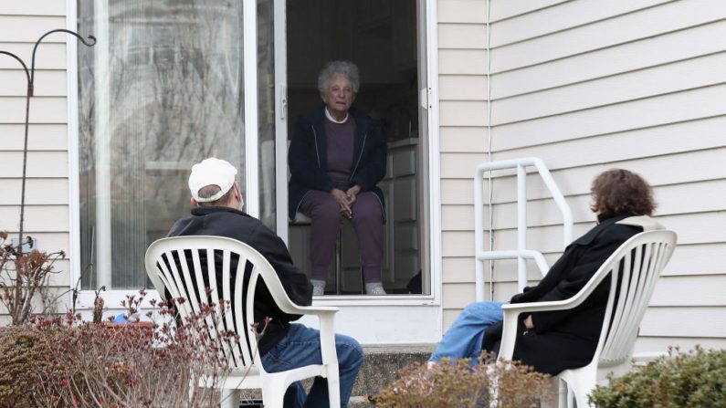 Un yerno y una hija visitan a su madre mientras practican el distanciamiento social en una casa de ancianos el 5 de abril de 2020 en East Meadow, Nueva York (EE.UU.). (Bruce Bennett/Getty Images)