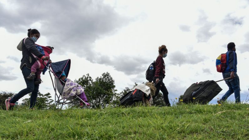 Migrantes venezolanos caminan con sus pertenencias por la autopista el 07 de abril de 2020 en Bogotá, Colombia. Miles de migrantes venezolanos que viven en Colombia han perdido sus trabajos y en algunos casos han sido desalojados de sus hogares debido a la recesión causada por el cierre para detener la propagación del virus del PCCh. (Guillermo Legaria/Getty Images)