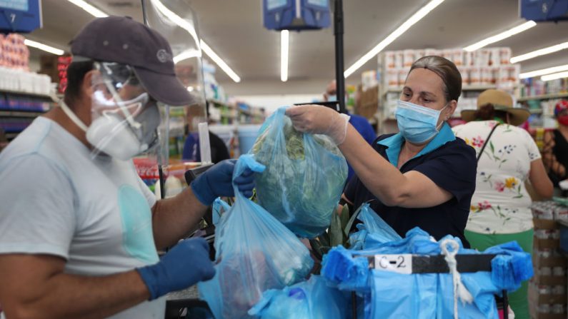 Una cajera usa mascarilla y guantes en el Supermercado Presidente en Miami, Florida, el 13 de abril de 2020. (Joe Raedle/Getty Images)
