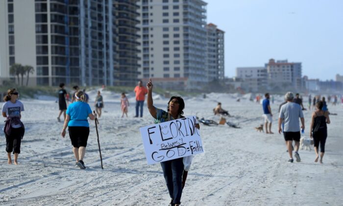 Una persona lleva un cartel en la playa de Jacksonville Beach, Florida, el 17 de abril de 2020. (Sam Greenwood/Getty Images)
